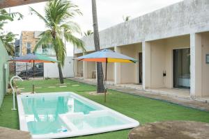 a swimming pool with two umbrellas and a swimming poolvisor at Flats Taiba Praia Centro in Taíba
