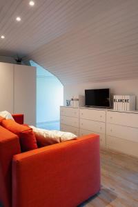sala de estar con sofá naranja y TV en B&B Maison Blanche, en Gante