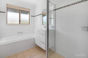 a bathroom with a tub and a sink and a shower at Parker by the Sea in Batemans Bay