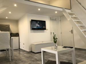 sala de estar con mesa blanca y TV en la pared en Magnifique studio neuf à la déco épurée., en Boussu