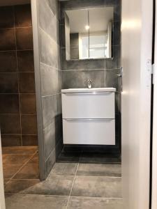 ein Badezimmer mit einem weißen Waschbecken und einem Spiegel in der Unterkunft Magnifique studio neuf à la déco épurée. in Boussu
