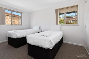 two beds in a room with two windows at Parker by the Sea in Batemans Bay
