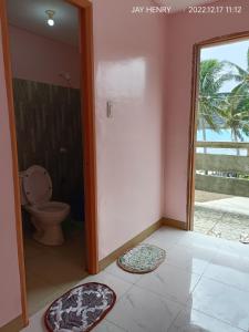 a bathroom with a toilet and a doorway with mats on the floor at Ocean View Room Jay Henry's Transient House in Pagudpud