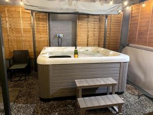 a bath tub with a bottle of wine in it at Cardiff Coach House with Hot Tub & Log Fire in Cardiff