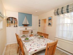 een eetkamer met een tafel met stoelen en een zeilboot aan de muur bij Winkle Cottage, Aldeburgh in Aldeburgh