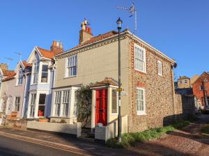 een stenen huis met een rode deur op een straat bij Winkle Cottage, Aldeburgh in Aldeburgh