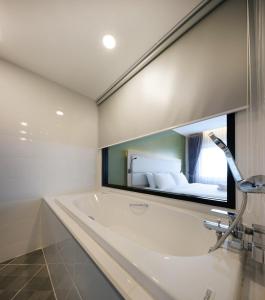 a bathroom with a tub and a large mirror at Prime Square Hotel in Chiang Mai
