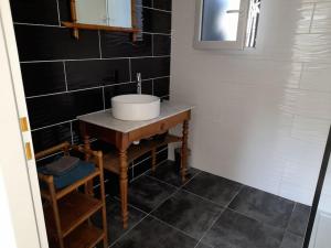 uma casa de banho com um lavatório e paredes em azulejos pretos em Les pins em Longeville-sur-Mer
