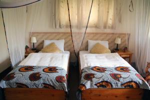 2 letti posti uno accanto all'altro in una camera da letto di Kluges Guest Farm a Kibale