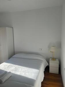 ein weißes Schlafzimmer mit einem weißen Bett und einer Lampe in der Unterkunft Casa Rural Bajadilla 5 in Atajate