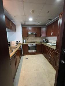 een keuken met houten kasten en een fornuis met oven bij relax room in King Abdullah Economic City