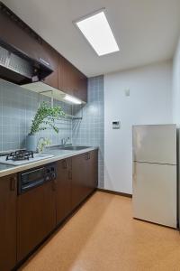 a kitchen with brown cabinets and a white refrigerator at Holiday Places /SHIBUYA 5min by train (Sangenjaya) in Tokyo