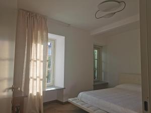 a white bedroom with a bed and a window at Casa Rocca in Roccaforte Mondovì