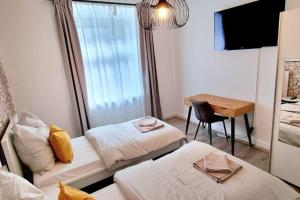 Habitación con 2 camas y mesa con escritorio. en Your Cozy Appartment in Wuppertal: Wupper-Home 2, en Wuppertal