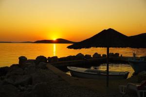 特孔Robinson house Vitane的海滩上的一艘船，带一把遮阳伞和日落