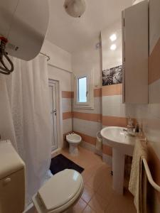 La salle de bains blanche est pourvue de toilettes et d'un lavabo. dans l'établissement Casa Minniti, à Syracuse