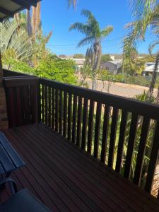 a wooden deck with a bench and palm trees at Kalbarri Reef Villa 3 in Kalbarri