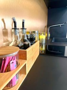 a kitchen with glass bottles on a wooden shelf at Maison Nina, Suite d’exception in Villeneuve-la-Garenne