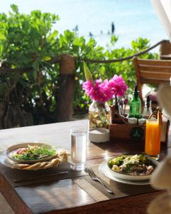 a table with two plates of food on a table with the beach at Aya Beach Resort in Kizimkazi