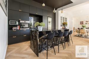 a kitchen with black cabinets and a bar with stools at Hôtel particulier - Le 119 in Valenciennes