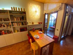 un comedor con una mesa de madera y un estante de libros en Matrioska House B&B, en Imola