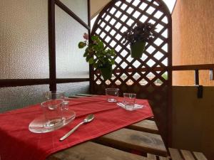 a table with a red table cloth and glasses on it at Matrioska House B&B in Imola