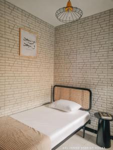 Bett in einem Zimmer mit Ziegelwand in der Unterkunft El jenna syariah villas in Colomadu