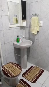 a white bathroom with a sink and a mirror at Apto com jeito de casa entre o mar e a montanha in Florianópolis