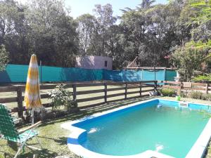 a swimming pool with an umbrella and a fence at Sueño Bonito in San Andrés de Giles