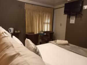 Habitación de hotel con cama y TV en sediba guest house en Krugersdorp