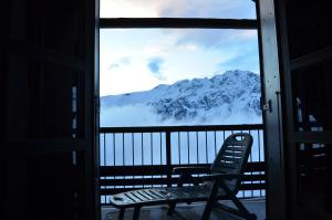 une chaise sur un balcon avec vue sur la montagne dans l'établissement Granges 32 - Beau Duplex spacieux, au pied des pistes Domaine Alpe d'Huez, à Villard-Reculas