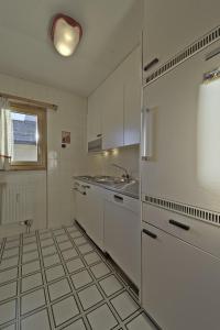 a kitchen with white appliances and a tile floor at Chesa Bursella - Madulain in Madulain