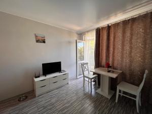 a living room with a television and a desk with a table at Studio SeaDream in Primorsko
