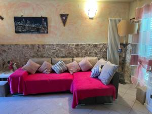 um sofá com cobertores e almofadas cor-de-rosa num quarto em Perfetto relax em Arena Metato