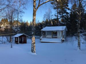 a cabin in the snow next to a tree at Spjutås Gård in Öxabäck