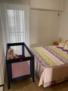 a baby crib with a teddy bear sitting next to a bed at DARISOL in Santa Pola +18 photos