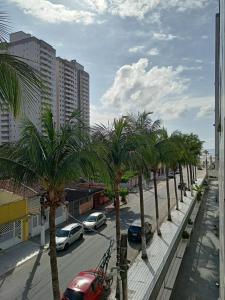 a street with palm trees in a city with cars at Kit Relu in Praia Grande