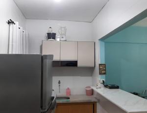 a kitchen with white cabinets and a refrigerator at Kit Relu in Praia Grande