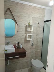 a bathroom with a toilet and a sink and a mirror at Kit Relu in Praia Grande