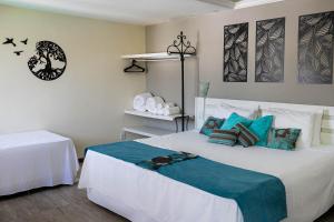 una camera da letto con un grande letto bianco con cuscini blu di Pousada Estalagem dos Corais da Prainha ad Arraial do Cabo