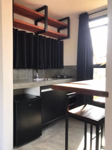 cocina con armarios negros y mesa de madera en Barong EcoVilla, en Barra Grande