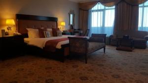 una habitación de hotel con una cama grande y una silla en Abha Palace Hotel en Abha