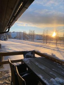 un banc en bois dans un champ enneigé avec le coucher du soleil dans l'établissement Himos Mökki, à Jämsä