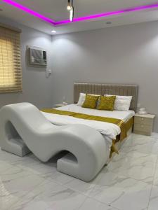 a white bedroom with a bed with a benchitures at شاليه الجبل الاحمر 3 in Al-ʿUla