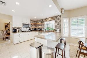 a kitchen with white cabinets and a counter with stools at Carlotta Haven in Palm Desert