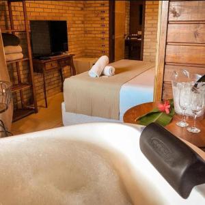 a bathroom with a tub and a bed and a television at Pousada Villa Verde - Frente para a Praia do Farol in Ilha do Mel