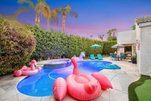 a swimming pool with inflatable flamingos in a backyard at Carlotta Haven in Palm Desert