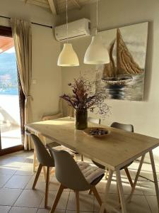 a dining room table with chairs and a vase of flowers at Poros endless view apartment in Poros +17 photos