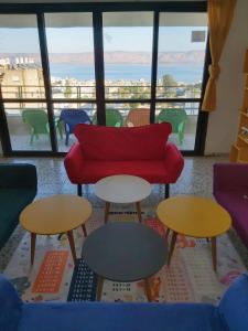 a living room with tables and a red couch at turtle guesthouse- tiberias in Tiberias