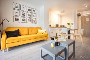 a living room with a yellow couch and a table at Apartament z kominkiem.. and SPA, MyWeek in Polanica-Zdrój